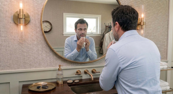 Man in bathroom mirror trying to remove mineral sunscreen white cast from his face and beard